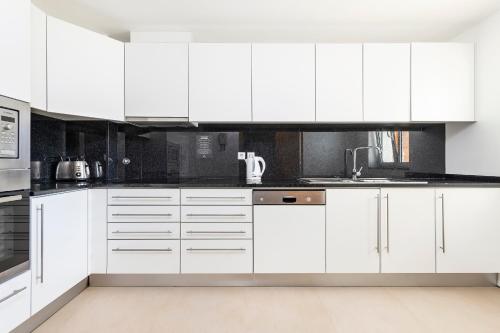 a kitchen with white cabinets and white appliances at Eden Resort in Albufeira
