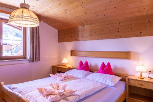 Un dormitorio con una cama con almohadas rosas. en Gästehaus Wötzer und Landhaus Stocka, en Grän