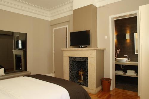 a bedroom with a bed and a fireplace with a television at Castilho House in Lisbon