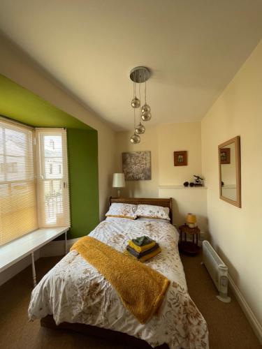 1 dormitorio con cama y pared verde en Coastal cottage ‘The Old Bank’ en Hartland