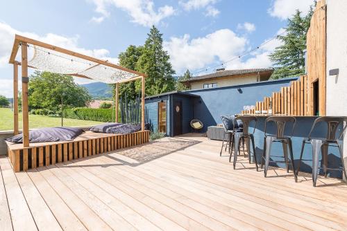 une terrasse en bois avec un bar et des chaises. dans l'établissement Cosy spirit-Proche plage, piste cyclable et centre village, 3ch 3 sdb- Une exclusivité LLA Selections by Location lac Annecy, à Saint-Jorioz