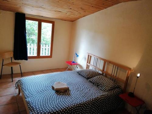Schlafzimmer mit einem Bett mit einer blauen und weißen Bettdecke in der Unterkunft Gîte en pleine nature proche du lac de la Gimone in Saint-Blancard