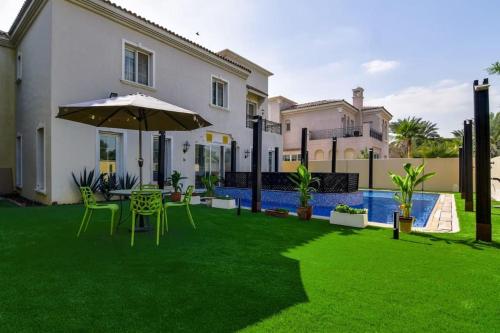 a lawn with an umbrella and a table and chairs at Frank Porter - Arabian Ranches in Dubai