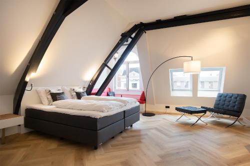 um quarto com uma cama grande e uma cadeira em Snoozz Hotels Bolsward Boutique hotel zonder receptie met digitale sleutel em Bolsward