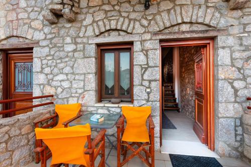 a patio with orange chairs and a table on a stone wall at Seaside Dukes Villas in Paralion astros