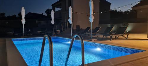 a swimming pool at night with chairs and umbrellas at House Vallis Aurea in Povile
