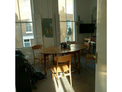 una mesa de comedor y sillas en una habitación con ventanas en Central London flat. Georgian Terrace. Bright., en Londres