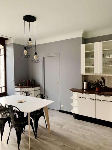 une cuisine avec une table blanche et des chaises noires dans l'établissement Maison entière aux portes du canal de Bourgogne, à Pouilly-en-Auxois