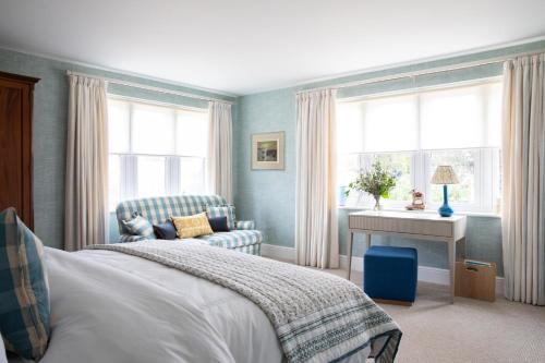 a bedroom with a bed and a chair and windows at Flint House - Goodwood Events in Chichester