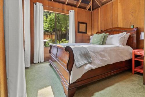 a bedroom with a wooden bed and a window at Cozy Creek Cabin - On Austin Creek Hot Tub - Dog Friendly - BBQ Grill - Fast WiFi in Cazadero
