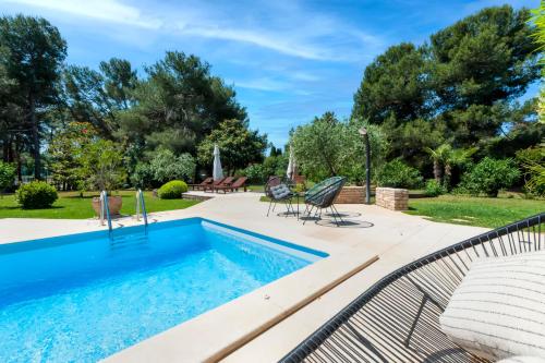 a swimming pool with two chairs and a table at Apartments Villa Rossella 1 in Rovinj