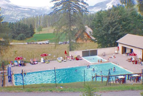 a large swimming pool with people sitting around it at Studio a Le Devoluy a 100 m des pistes avec balcon amenage et wifi in Le Dévoluy