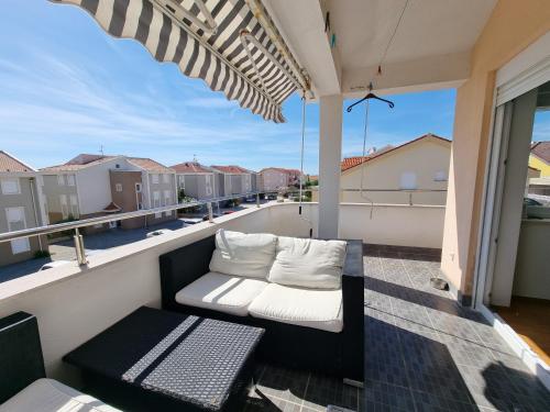 a balcony with a white couch on a balcony at SUNNY BALCONY TERRACE Apartment in Novalja
