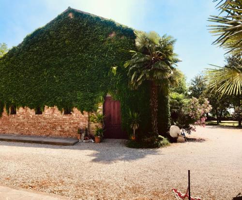a building covered in ivy with a red door at LA GASTALDIA in Pontecasale