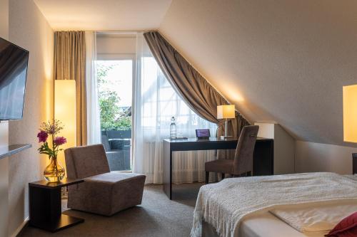 a hotel room with a bed and a desk and a window at Ganter Hotel & Restaurant Mohren in Reichenau