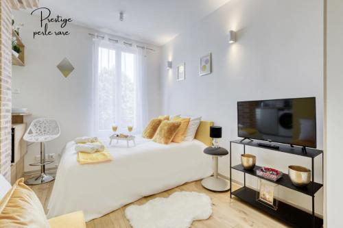 - une chambre blanche avec un grand lit et une télévision dans l'établissement escalade romantique 5 min de Paris, à Ivry-sur-Seine