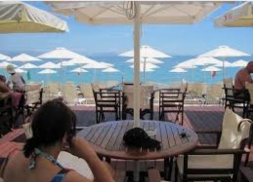 バルバティにあるVASILIKI SeaMemoriesの傘をさしてテーブルの前に座る女性