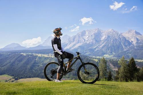 a person standing next to a bike on a field at Holzhackerin - the charming Haus am Berg in Schladming