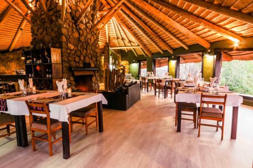 a dining room with tables and chairs and a fireplace at Ondudu Safari Lodge in Omaruru