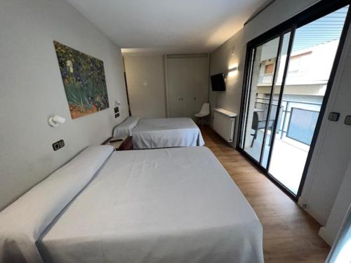 a bedroom with two beds and a large window at Hostal Crisami in Solsona