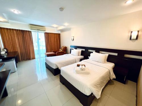 a hotel room with two beds and a chair at Hotel La Villa Khon Kaen in Khon Kaen