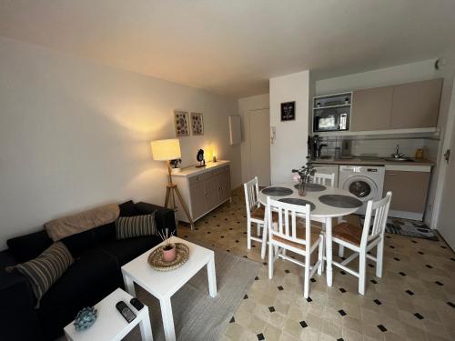 Una sala de estar con un sofá, una mesa y sillas. en Une parenthèse à dives sur mer, en Dives-sur-Mer