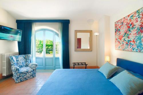 a bedroom with a blue bed and a chair and a window at Residenza Ca De Frati in Arezzo
