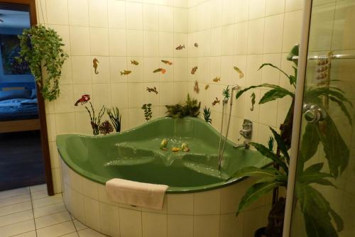 a bathroom with a green bath tub with plants at Schreiner in Daun