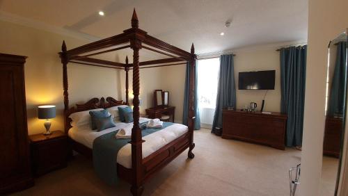 a bedroom with a canopy bed and a television at The Trewythen in Llanidloes