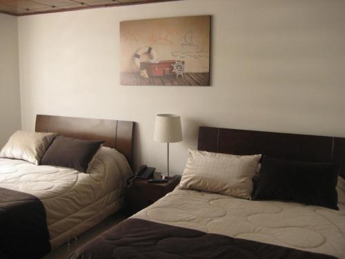 a bedroom with two beds and a painting on the wall at Hotel Casa Santa Marta in Bogotá