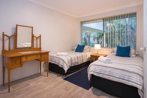 a bedroom with two beds and a desk and a mirror at Beach & Trees, beachfront Siesta Park in Busselton