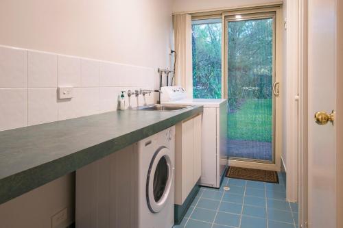 a kitchen with a sink and a washing machine at Beach & Trees, beachfront Siesta Park in Busselton