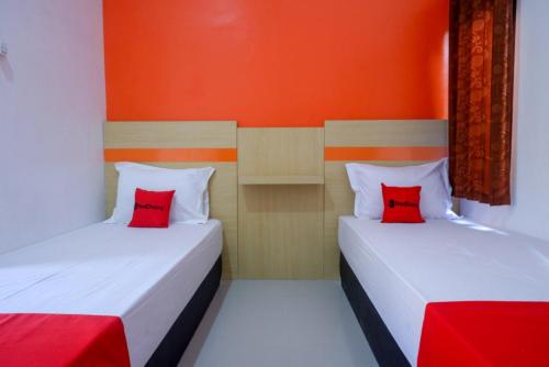 two beds with red pillows in a room at RedDoorz Syariah near Alun Alun Kota Rembang in Rembang