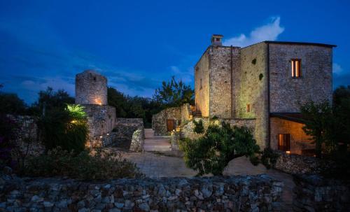 un antiguo edificio de piedra con dos torres por la noche en Masseria Montepaolo Dimora di Charme, en Conversano