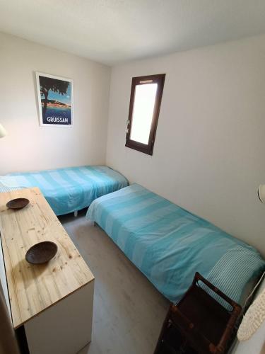 une chambre avec deux lits, une table et un bureau dans l'établissement Appartement avec Piscine et Tennis St Pierre La Mer - 4TMED207I, à Saint Pierre La Mer