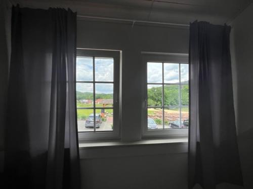 a room with two windows and a view of a parking lot at Hotel Rehkitz in Halle Westfalen