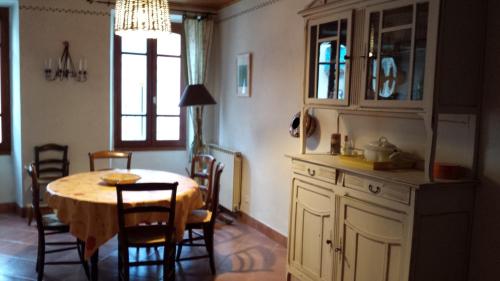une cuisine et une salle à manger avec une table et des chaises dans l'établissement La maison de grand-mère Angèle, à Saint-Jean-du-Bruel