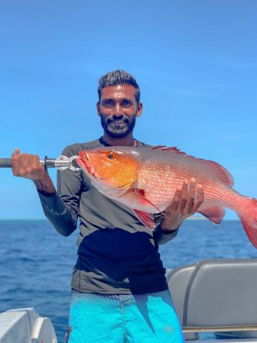 a man holding a fish on a boat at The Pearl Seaview in Fulidhoo