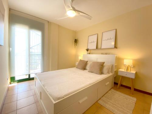 a bedroom with a large white bed and a window at Vistas al mar playa Eucaliptus, con solarium privado in L'Eucaliptus