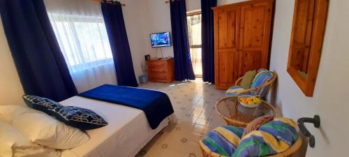 a bedroom with a bed and two chairs and a television at Villa Bronja Studio airconditioned apartment Xlendi in Xlendi