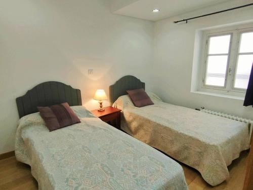 une chambre avec deux lits et une lampe sur une table dans l'établissement Appartement 3 pièces à Cauterets, proche thermes et télécabine, avec wifi et parking - FR-1-234-144, à Cauterets