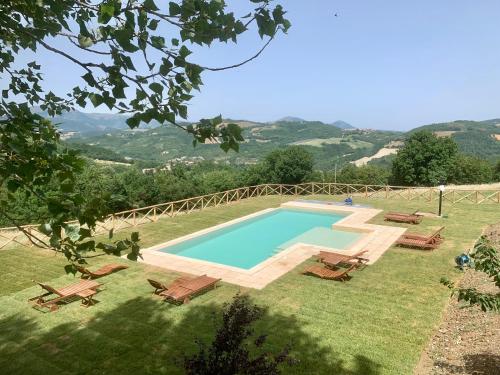 a swimming pool in a field with chairs around it at Agriturismo Fonte Rosa in Fiastra