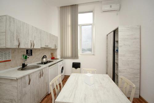 a white kitchen with a table and a sink at Hostel Mandaria in Kutaisi