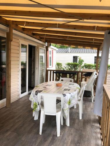 a patio with a table and chairs on a deck at MOBIL HOME - 6 Pers - LES CHARMETTES **** in Les Mathes