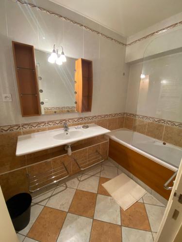 une salle de bain avec un lavabo, une baignoire et un miroir dans l'établissement HOME LE SOFT Vic sur Cère, à Vic-sur-Cère