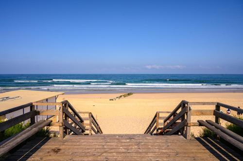 une promenade en bois menant à une plage avec l'océan dans l'établissement La Cabane de Jeanne ~ 10 minutes à pied de l'océan, à Mimizan
