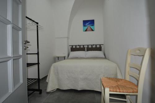 um quarto branco com uma cama e uma cadeira em Casa giulia em Ostuni