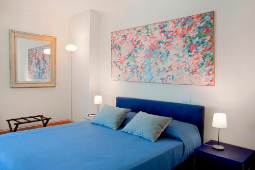 a bedroom with a blue bed with a large painting on the wall at Residenza Ca De Frati in Arezzo