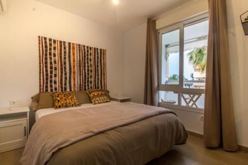 Schlafzimmer mit einem großen Bett und einem Fenster in der Unterkunft Vistamarina B 211 By IVI Real Estate in Torremolinos