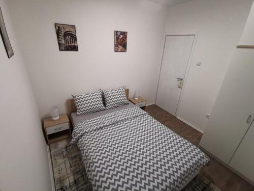 a small bedroom with a bed and two tables at White House NS in Novi Sad